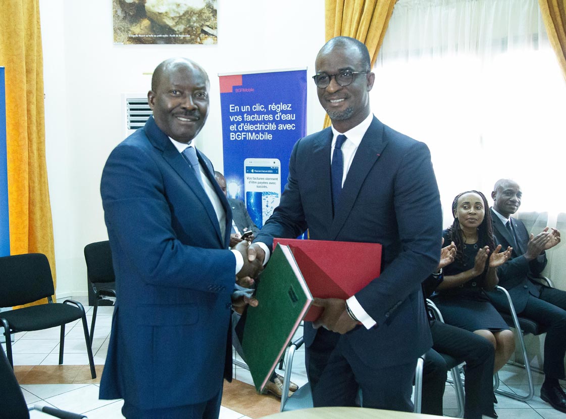 Henri Claude OYIMA et Stanislas ZEZE TEBILY procédant à l’échange des documents au terme de la signature.