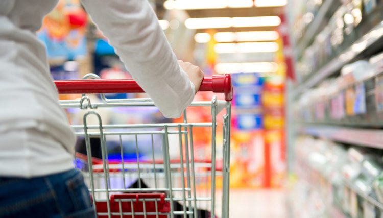 A young woman pulling a shopping cart in a mall. Extreme shallow DOF with focus on her hands."n